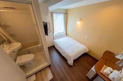 a small bathroom with a bed and a toilet at ELE Hotel \u6771\u4e0a\u91ce in Tokyo