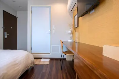 a bedroom with a bed and a wooden desk at ELE Hotel \u6771\u4e0a\u91ce in Tokyo