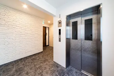 a hallway with a white brick wall and elevators at GIVE Shibuya Honmachi in Tokyo