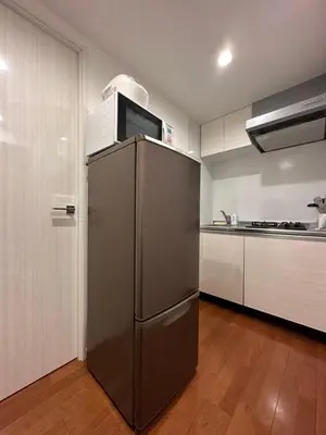 a kitchen with a stainless steel refrigerator with a microwave on top at nestay inn tokyo ryogoku in Tokyo