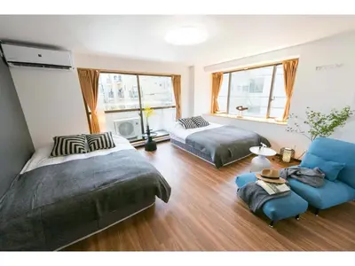 a bedroom with two beds and a blue couch at Tora Hotel Rikugien - Vacation STAY 52741v in Tokyo