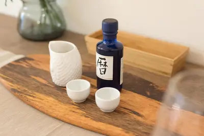 a bottle of wine and three cups on a wooden cutting board at Tora Hotel Ueno - Vacation STAY 52811v in Tokyo