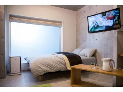 a bedroom with a bed and a television on a wall at bmj Shinjuku Okubo - Vacation STAY 46884v in Tokyo