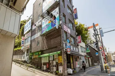 a building with signs on the side of a street at \u3055\u304f\u3089\u30a4\u30f3\u99c5\u524d\u7652\u3084\u3057\u7a7a\u9593 in Tokyo