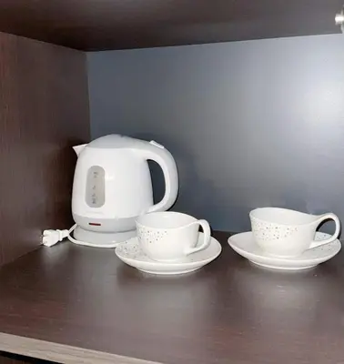 two cups and saucers on a shelf with a tea kettle at Hotel Plaisir Akihabara in Tokyo