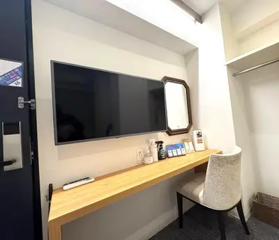 a large flat screen tv on a wall with a chair at Hotel Plaisir Akihabara in Tokyo