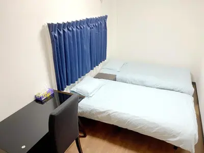 a room with two beds and a desk and blue curtains at SKYE HOME MINPAKU - Vacation STAY 11856 in Tokyo