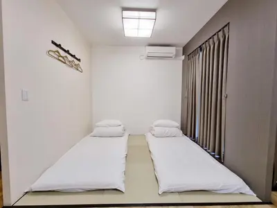 two beds in a white room with a window at KYU KYU HOTEL in Tokyo