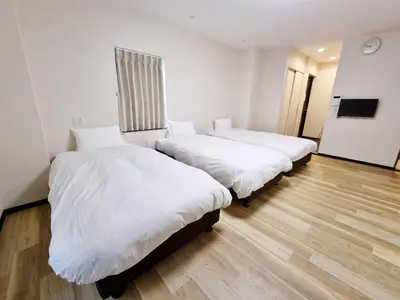 three beds in a room with white sheets at KYU KYU HOTEL in Tokyo