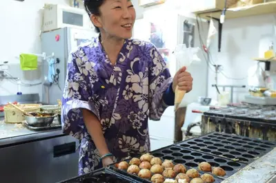 a woman standing in a kitchen cooking food on a grill at \u8461\u8404\u306e\u9577\u5c4b in Tokyo