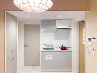 a kitchen with white cabinets and a chandelier at japan house nishishinjuku in Tokyo