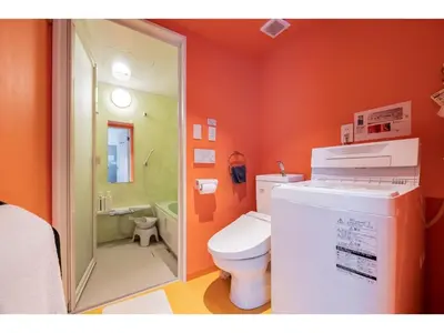 an orange bathroom with a toilet and a shower at bmj Shinjuku Okubo - Vacation STAY 68278v in Tokyo