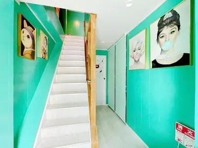 a staircase in a house with blue walls and posters at Hotel Tiffany in Tokyo