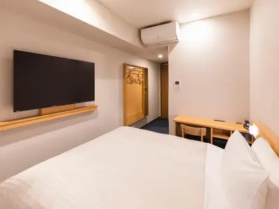 a hotel room with a bed and a flat screen tv at Sotetsu Fresa Inn Daimon in Tokyo