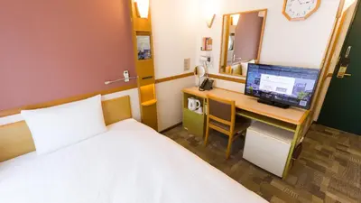 a bedroom with a bed and a desk with a computer at Toyoko Inn Tokyo Shinagawa-eki Takanawa-guchi in Tokyo