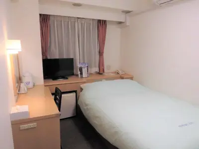 a hotel room with a bed and a desk with a television at Olympic Inn Shibuya in Tokyo