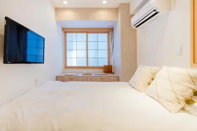 a bedroom with a white bed and a flat screen tv at STone Hotel in Tokyo