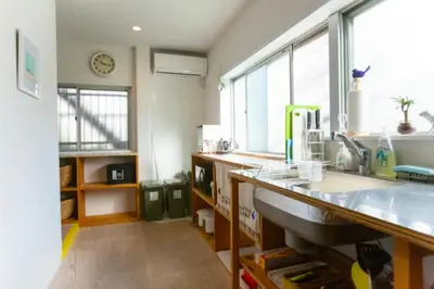 a kitchen with a counter and a sink and windows at &y Kitasenju in Tokyo