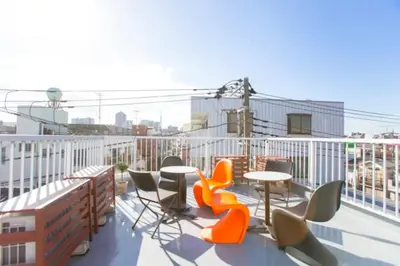 a balcony with tables and chairs on a building at &y Kitasenju in Tokyo