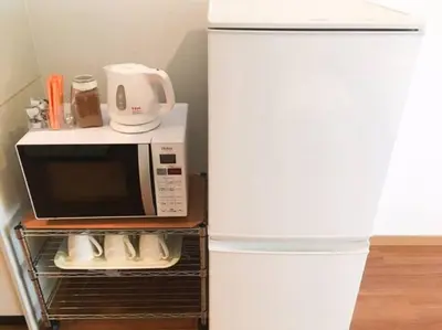 a white microwave oven sitting next to a refrigerator at Goodsite In Oshiage in Tokyo