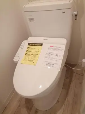 a white toilet with a yellow sign on the lid at Great location Only 1 minute to St G-18 Ginza Line in Tokyo
