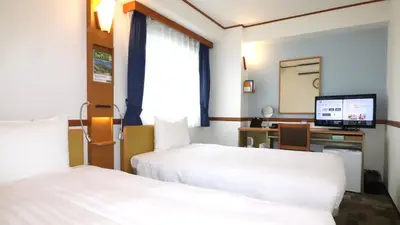 a hotel room with two beds and a desk with a computer at Toyoko Inn Tokyo Monzen-nakacho Eitaibashi in Tokyo