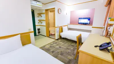 a room with two beds and a desk with a phone at Toyoko Inn Nihombashi Bakurocho in Tokyo