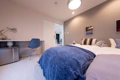 a bedroom with two beds and a blue chair at Shinjuku ICE MOUNTAIN GUEST HOUSE in Tokyo