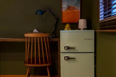 a kitchen with a white refrigerator and a wooden chair at Shinjuku ICE MOUNTAIN GUEST HOUSE in Tokyo