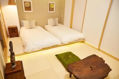 a room with two beds and a wooden table at Asakusa New City Hotel in Tokyo