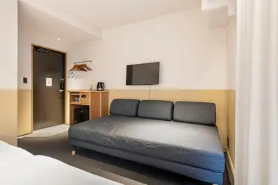 a bedroom with a bed and a flat screen tv at Hotel Asakusa KANNONURA in Tokyo