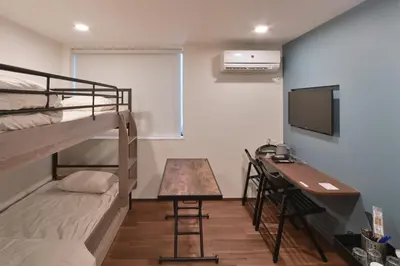 a room with bunk beds and a desk and a television at Stylewood Nishi-Shinjuku by Tranova in Tokyo