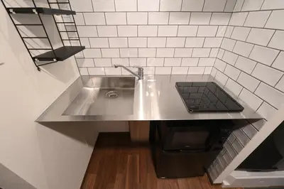 a stainless steel sink in a kitchen with white tiles at Stylewood Nishi-Shinjuku by Tranova in Tokyo
