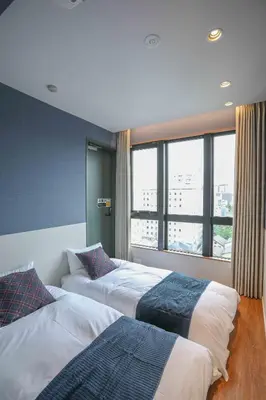 two beds in a room with a large window at the Moto Hotel Asakusa in Tokyo