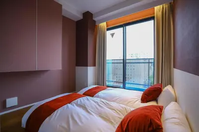 a bedroom with two beds and a large window at the Moto Hotel Asakusa in Tokyo