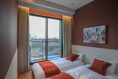 two beds in a room with a large window at the Moto Hotel Asakusa in Tokyo