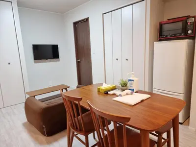 a kitchen with a wooden table with chairs and a refrigerator at PRISM Inn Kamata in Tokyo