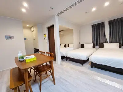 a hotel room with two beds and a wooden table at PRISM Inn Kamata in Tokyo