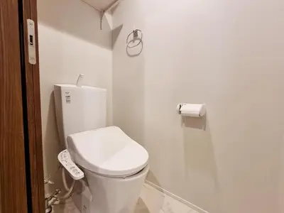 a white bathroom with a toilet and a roll of toilet paper at Lien \u897f\u65b0\u5bbf in Tokyo