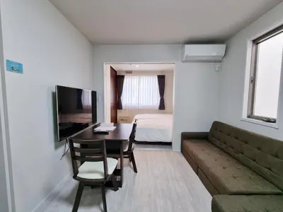 a room with a table and a couch and a bedroom at Lien \u897f\u65b0\u5bbf in Tokyo