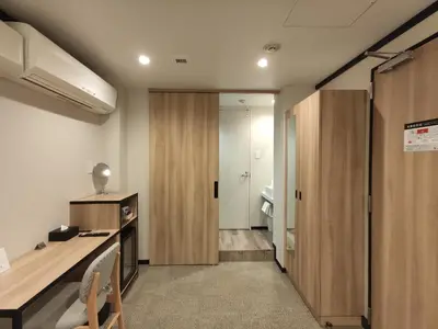 a hotel room with a desk and a bathroom at yksi SAUNA & STAY in Tokyo