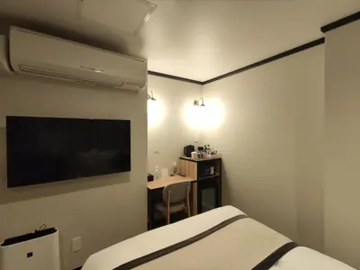 a hotel room with a bed and a television at yksi SAUNA & STAY in Tokyo