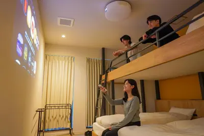 two people playing a video game in a hotel room at COB HOTEL Asakusa in Tokyo