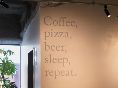 a sign that reads coffee pizza beer sleep repeat on a wall at all day place shibuya in Tokyo