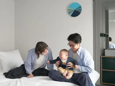 a man and woman sitting on a bed with a baby at all day place shibuya in Tokyo