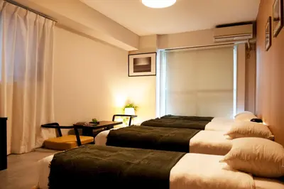 a hotel room with three beds and a table at renovated in June 2025 apartment 3mins walk to station 1stop to Shinjuku 3stop to Shibuya in Tokyo