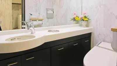 a bathroom with a sink and a toilet and flowers at Toyoko Inn Tokyo Nihombashi Zeimusho Mae in Tokyo