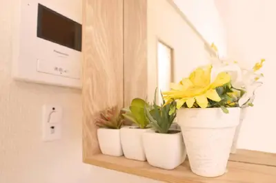 three white vases with flowers sitting on a shelf at Tokyo Stay Excel Shinjuku in Tokyo