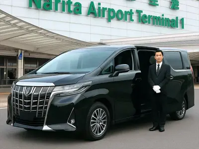 a man in a suit standing next to a black suv at YADOYA Ryusenjicho in Tokyo