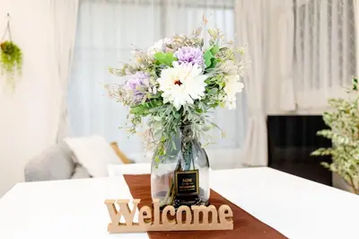 a vase of flowers on a table with a welcome sign at The Felice Uguisudani - Vacation STAY 96221 in Tokyo